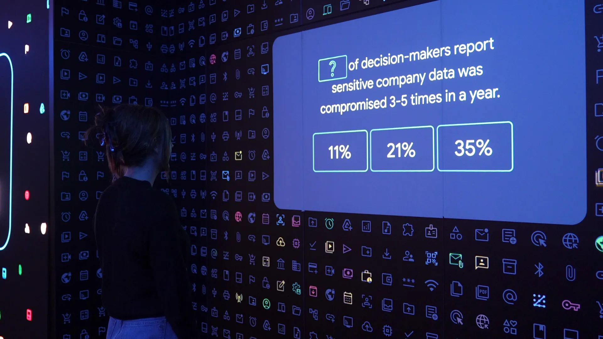 A woman standing in front of a projection mapped wall that displayed statistics releated to cybersecurity in the form of a Quiz